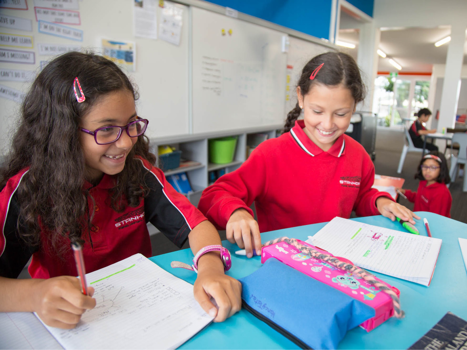 two young students smiling and working at a desk